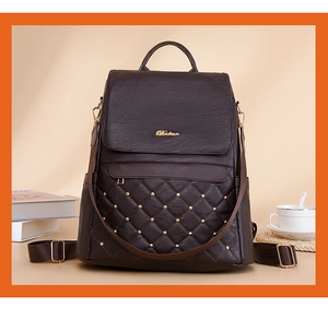 Detail of vintage brown leather backpack with quilted pattern and gold stud accents