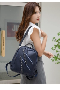 Detail of dark blue PU leather backpack with decorative zippers and metal rivets