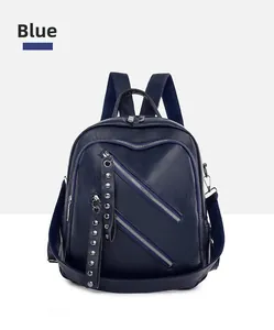 Detail of dark blue PU leather backpack with diagonal zippers and silver metal rivets