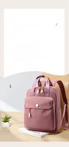 Detail of dusty pink nylon backpack showing adjustable straps and front zip pocket