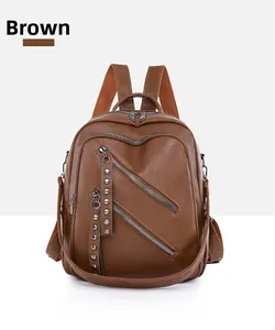 Detail of brown PU leather backpack featuring silver rivets and dual zipper pockets