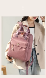 Detail of dry rose pink nylon backpack with wide woven straps and logo on a model