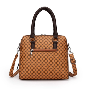 Brown vintage handbag with geometric print and adjustable shoulder strap on white background