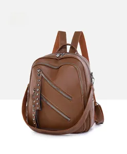 Detail view of brown pebbled leather backpack with silver zippers and metal rivets