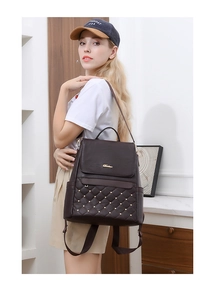 Detail of dark brown quilted backpack with gold rivets worn by model in casual setting