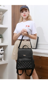 Detail of black quilted leather backpack with gold rivets and logo on a female model