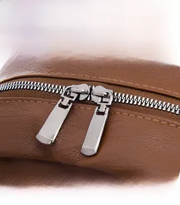 Detailed macro view of high-quality brown PU leather texture and dual metal zippers
