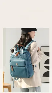 Detail of teal nylon backpack showing brown leather pullers and branded jacquard straps
