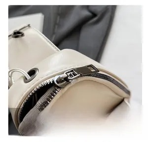 Detail showing smooth metal zipper and fine stitching on a beige PU leather crossbody bag