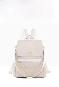 Front detail of beige leather backpack with quilted pattern, gold studs, and brand logo