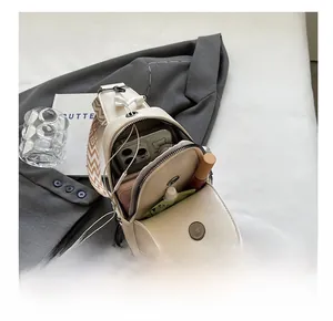 Interior storage of cream PU leather crossbody bag showing phone and accessories