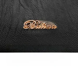 Detail of rose gold Balina logo on high-quality black lychee grain leather backpack