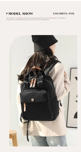 Rear view of model wearing a black nylon backpack with brown leather accents and FOX straps