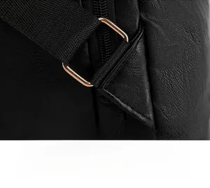 Detail of reinforced triangle stitching and gold D-ring on black leather backpack