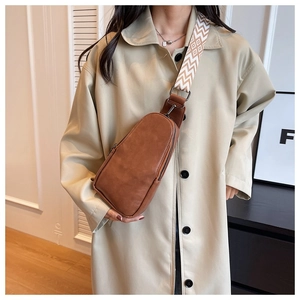 Brown faux leather chest bag with wide geometric pattern woven strap on female model