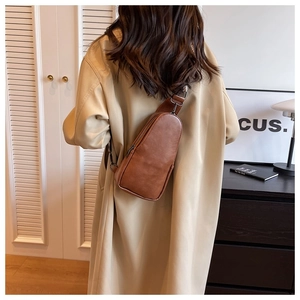 Rear view of a model wearing a brown vintage PU leather sling bag with adjustable strap