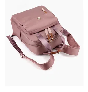 Detail of dusty pink nylon backpack with multi-zipper pockets and woven logo strap