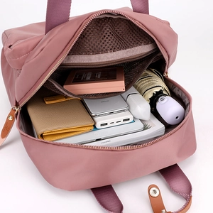 Detail of grey-pink nylon backpack showing spacious interior compartments for travel essentials