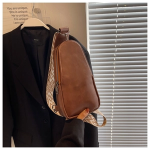 Detail of a brown PU leather crossbody bag with a wide vintage geometric patterned strap