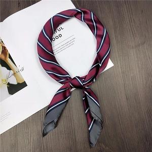 Close-up of a striped silk scarf tied in a bow on a wooden surface and magazine
