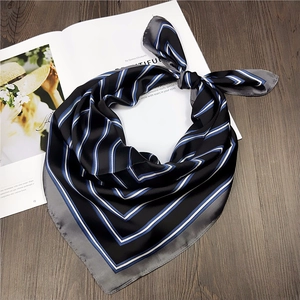 Detail of striped silk scarf tied on a magazine with elegant black and blue satin texture