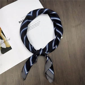 Close-up of a striped square silk scarf tied on a magazine with a wooden backdrop