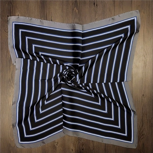 Detail of square silk scarf showing geometric blue and white stripes on black fabric
