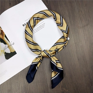 Detail view of a golden yellow striped silk scarf tied in a stylish knot on wood
