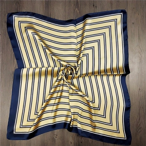 Detail of striped silk-feel square scarf with navy and gold geometric pattern texture