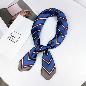 Detail showing the smooth silk texture and V-shaped striped pattern on the navy blue scarf