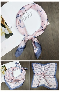 Detailed view of pink square silk scarf with blue flamingo print and navy hemmed edges