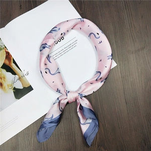 Pink silk square scarf with blue flamingo prints on a wooden table with magazine