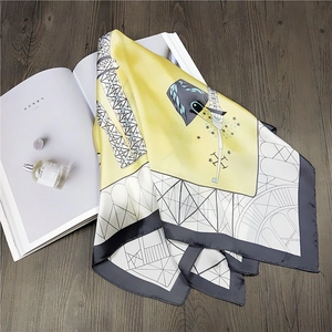 Detailed view of yellow and white square silk scarf with Eiffel Tower print on a wooden table