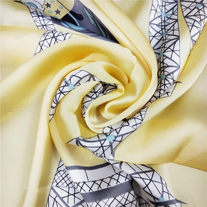 Close-up of bright yellow silk square scarf showing soft satin texture and geometric prints
