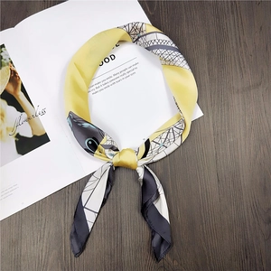 Elegant yellow and grey geometric silk square scarf draped on a stylish magazine