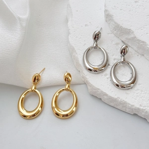 Boucles d'oreilles ovales dorées et argentées polies sur un socle en pierre élégant