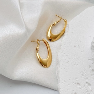 Modern gold U-shaped hoop earrings with ribbed texture on elegant silk background
