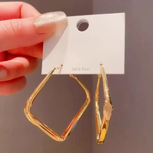 Close-up of large geometric gold square hoop earrings featuring S925 silver posts