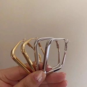 Close-up of geometric square hoop earrings in polished gold and silver finishes