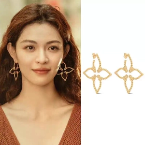 Detailed close-up of hollow four-leaf clover hoop earrings with twisted rope texture
