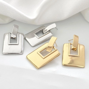 Boucles d'oreilles rectangulaires minimalistes or et argent sur un support en marbre blanc