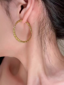 Dettaglio di grandi orecchini a cerchio in oro 18K con trama intrecciata per donna