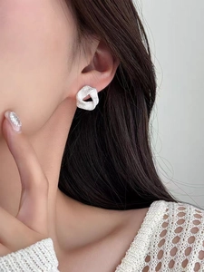 Gros plan de boucles d'oreilles nœuds argentées minimalistes sur modèle, fini mat