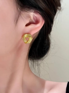 Gros plan de boucles d'oreilles triangles dorées torsadées avec finition brossée mate