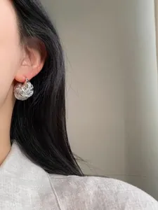 Close-up of silver coiled twist rope earrings on model showing artistic spiral design