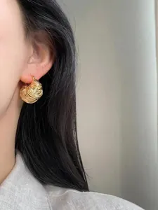 Detailed macro view of gold U-shaped spiral coil brass earrings worn by a model