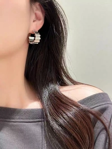 Close-up of silver geometric C-shape earring with vertical ridges on model's ear