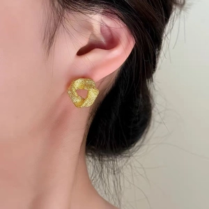 Boucles d'oreilles triangles minimalistes dorées au fini mat portées par modèle