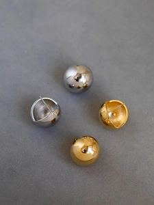 Detailed view of polished 18K gold and silver sphere earrings with glossy mirror finish