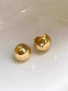Detailed view of polished 18K gold spherical earrings with mirror finish and secure pin